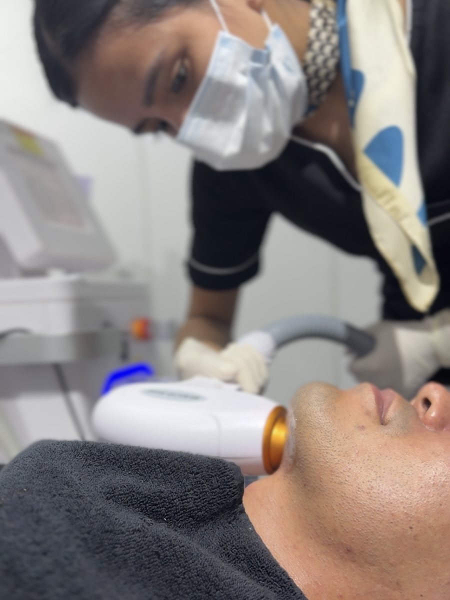 A therapist performing laser hair removal on a client's chin