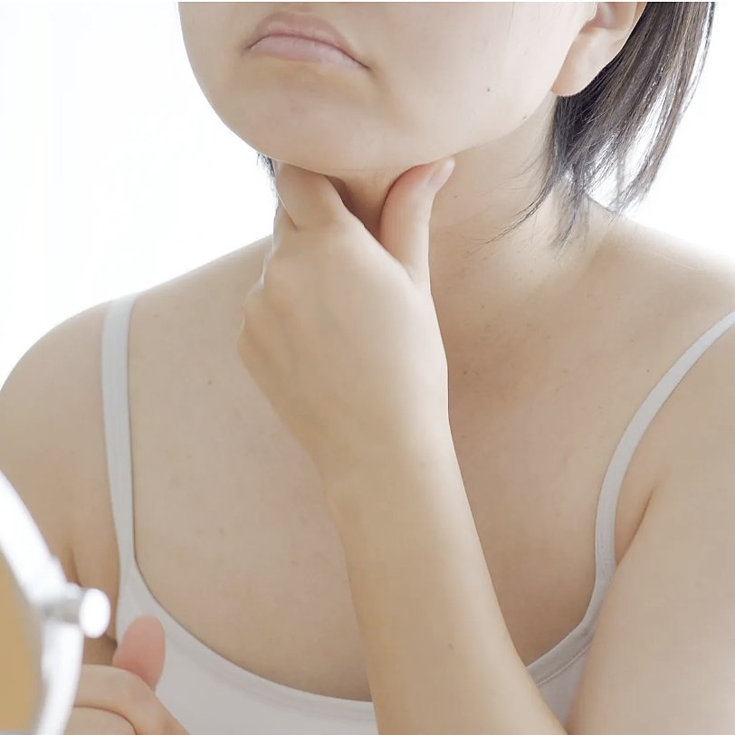 A woman checking her jawline and under-chin in a mirror