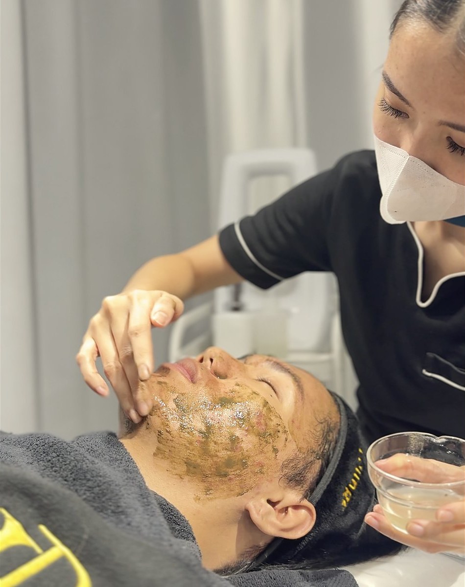 A therapist applying matcha peel to a client's face