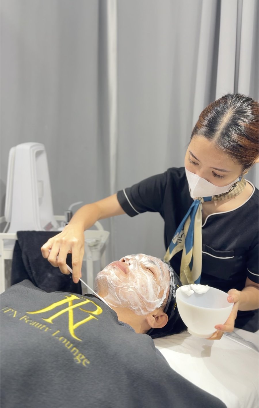 A therapist cleansing a client's face with foam