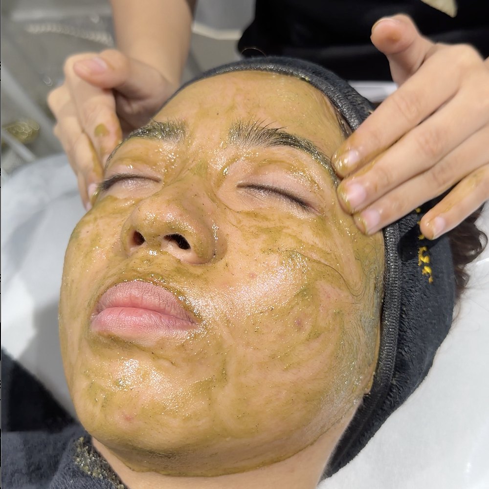 A therapist applying matcha peel to a client's face